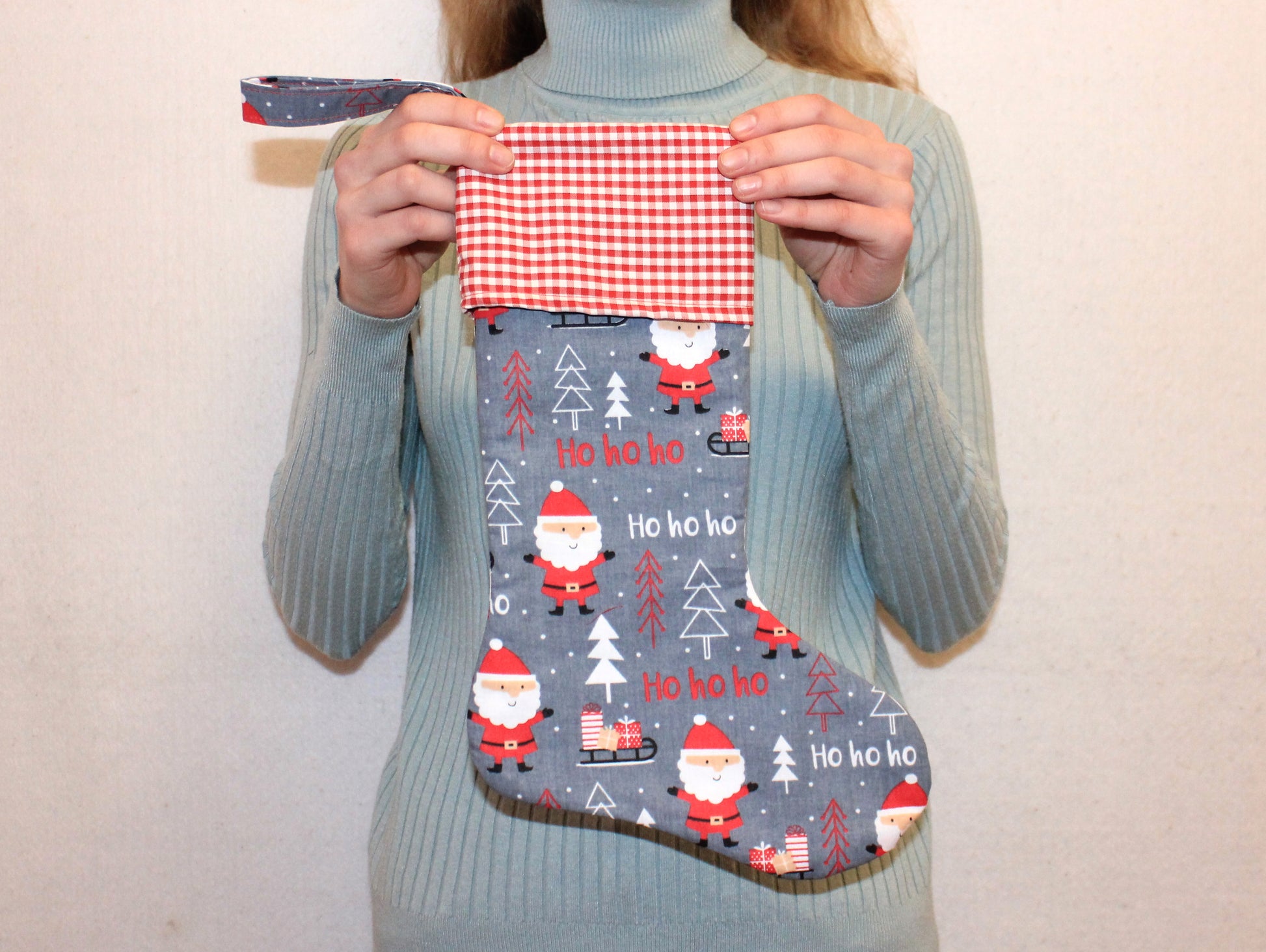 Person holding a Christmas-themed stocking with Santa Claus and trees - sewing tutorial with template by NatkoPatterns