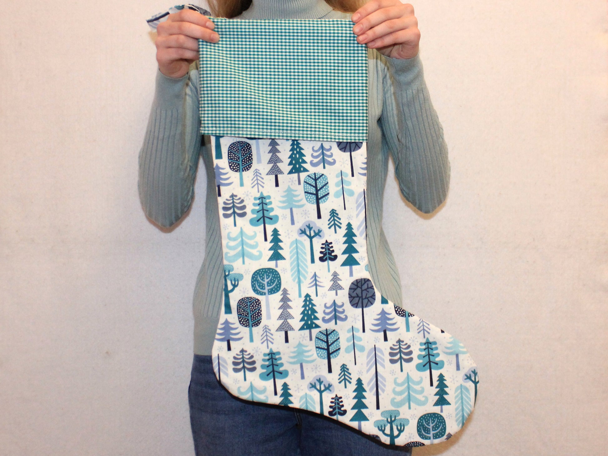 Person holding a blue and white patterned Christmas sock