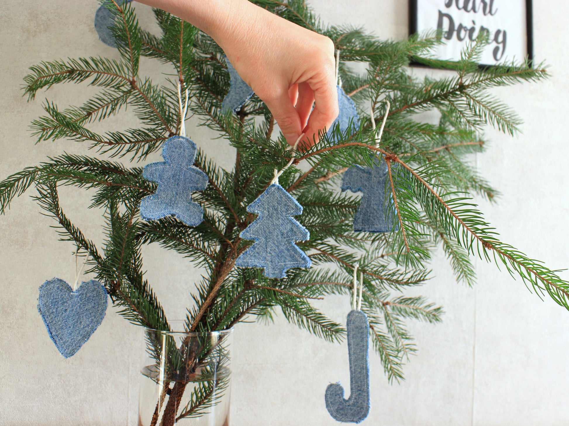 Hand arranging blue ornaments shaped like hearts, trees - Sustainable decor pattern
