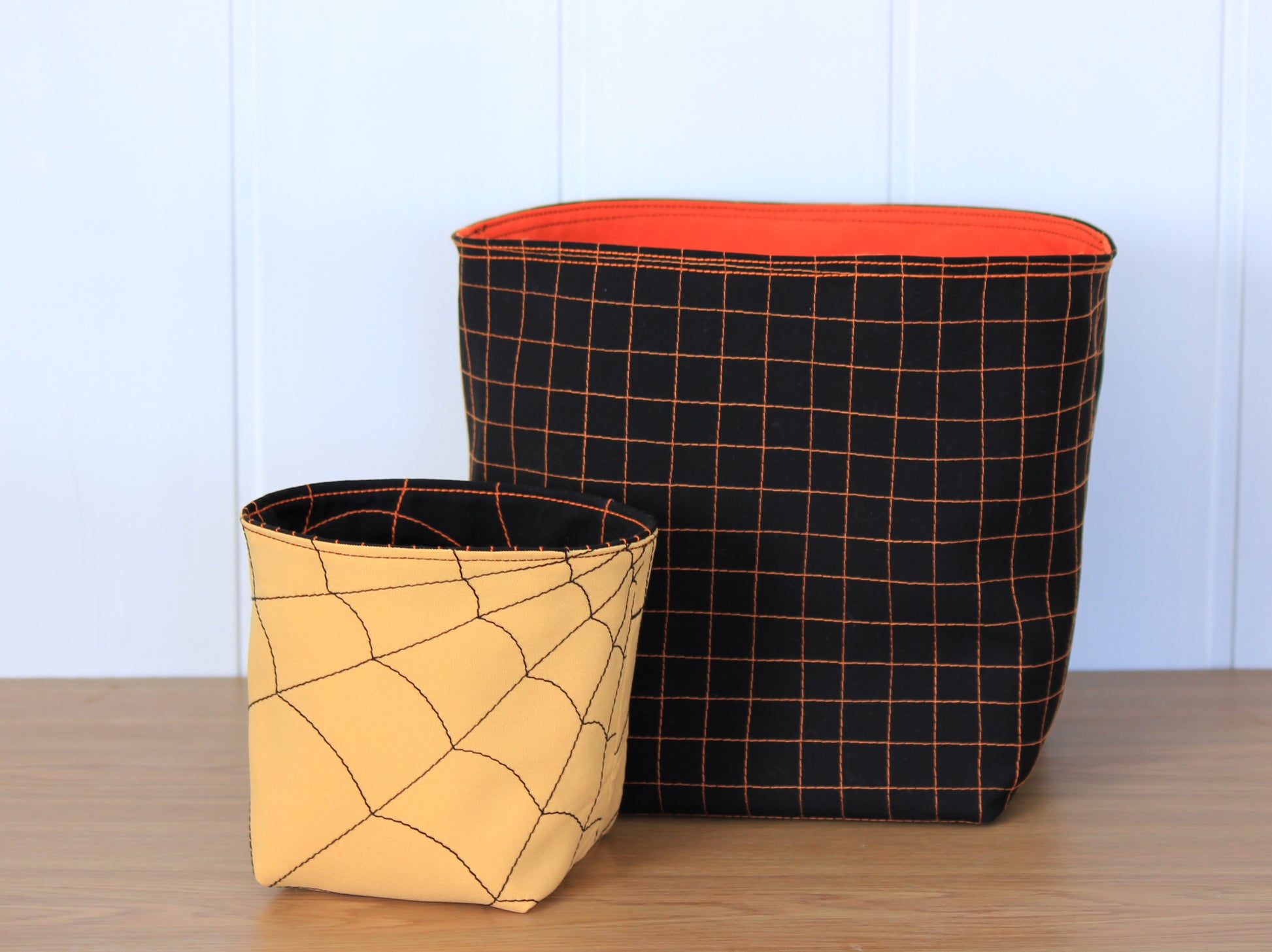 Two fabric baskets, one with a spider web pattern and the other with a grid design - Halloween sewing pattern
