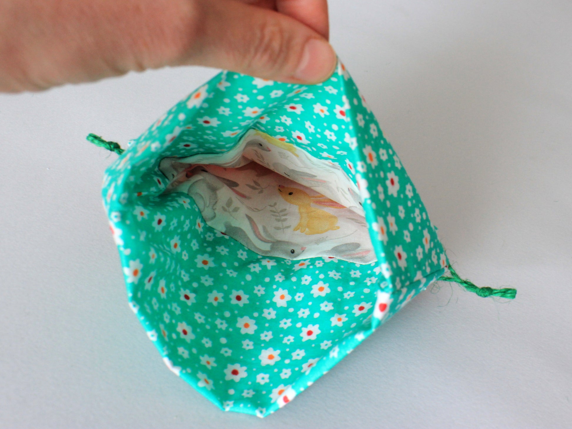 Green drawstring bag with floral pattern containing baby wipes on a white background