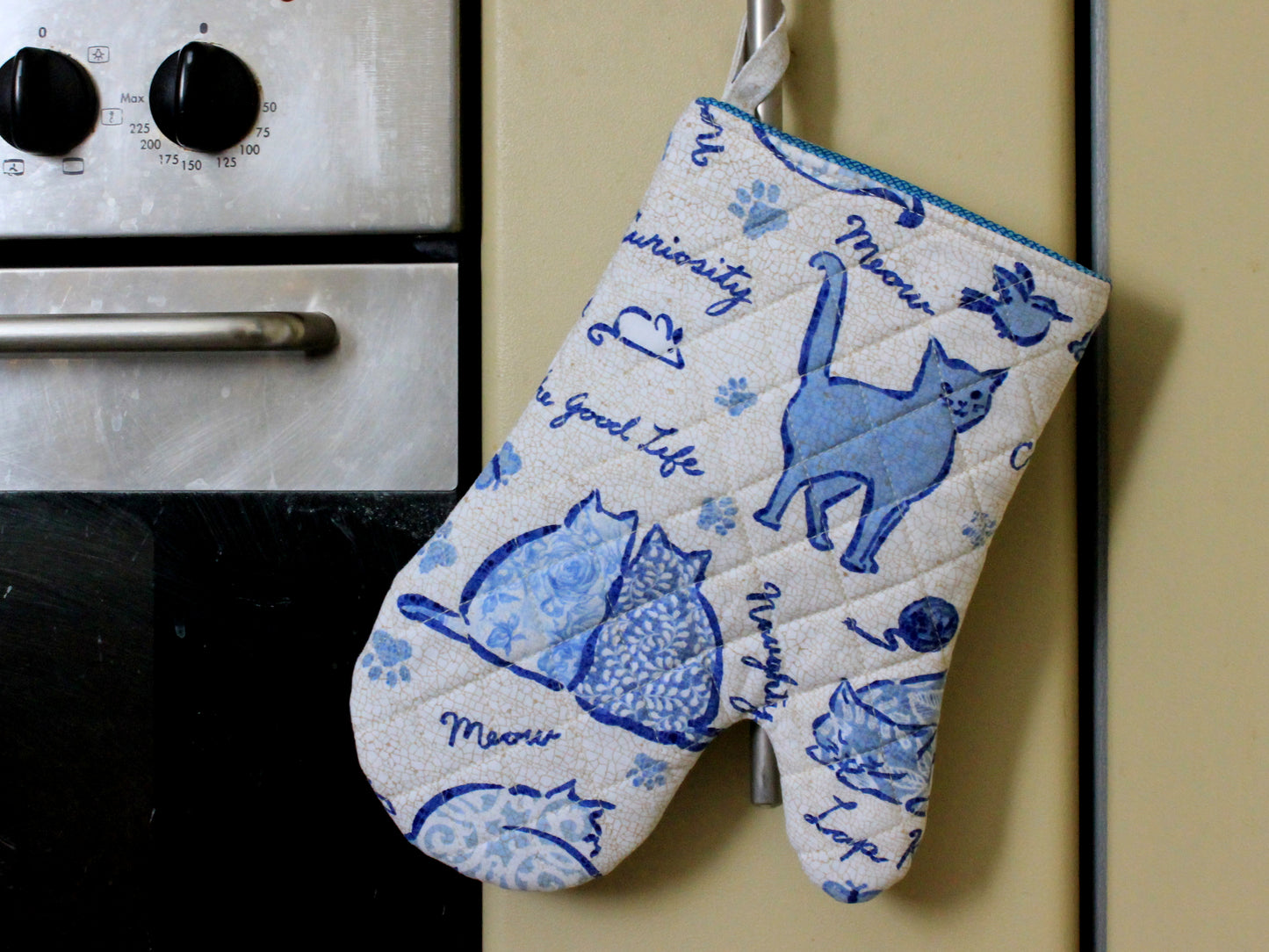 Handmade quilted oven mitt hanging in kitchen interior