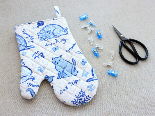Quilted oven mitt sewing project with fabric clips and sewing scissors