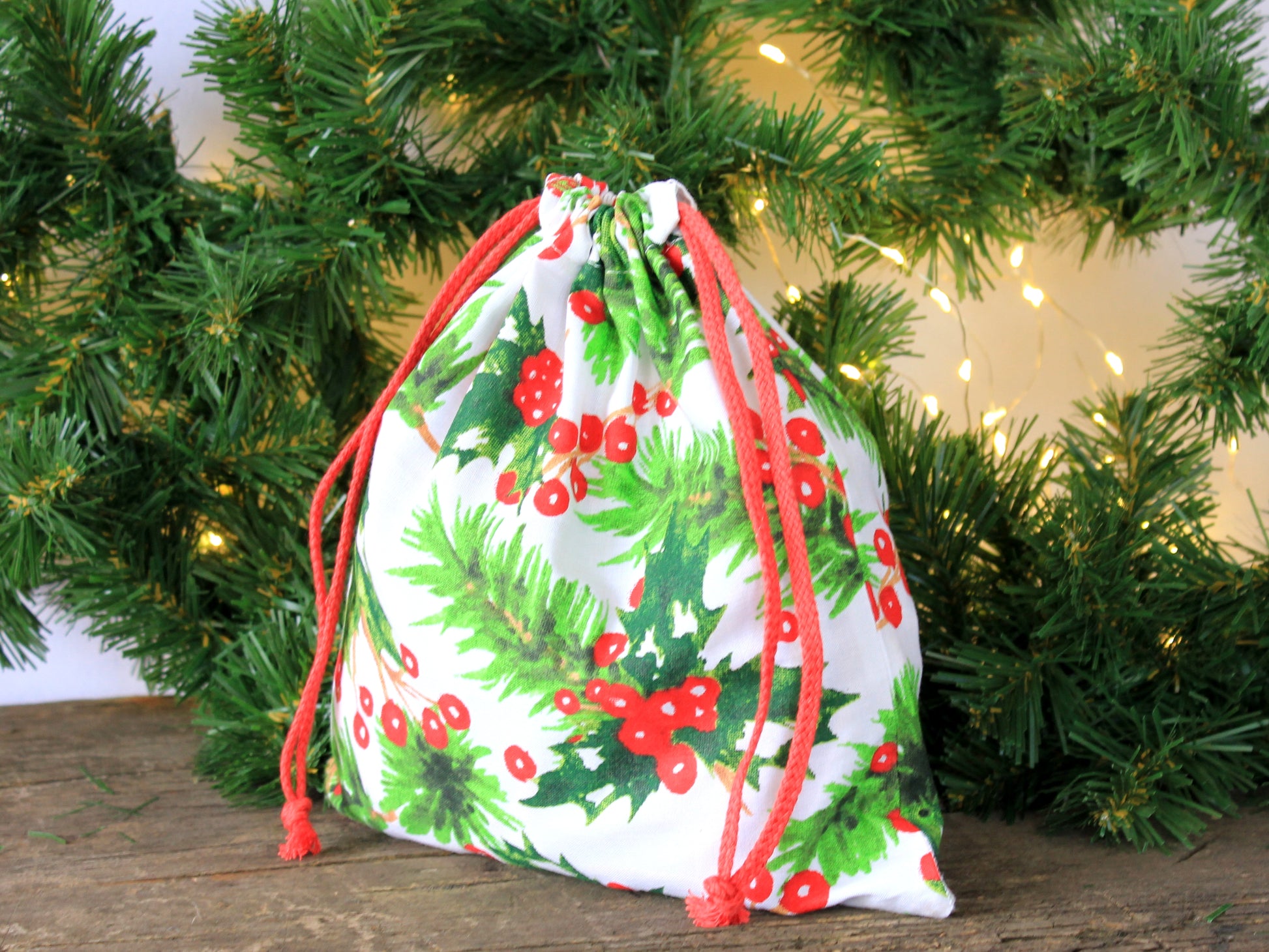 Drawstring bag with holly design in front of a Christmas tree - sewing pattern
