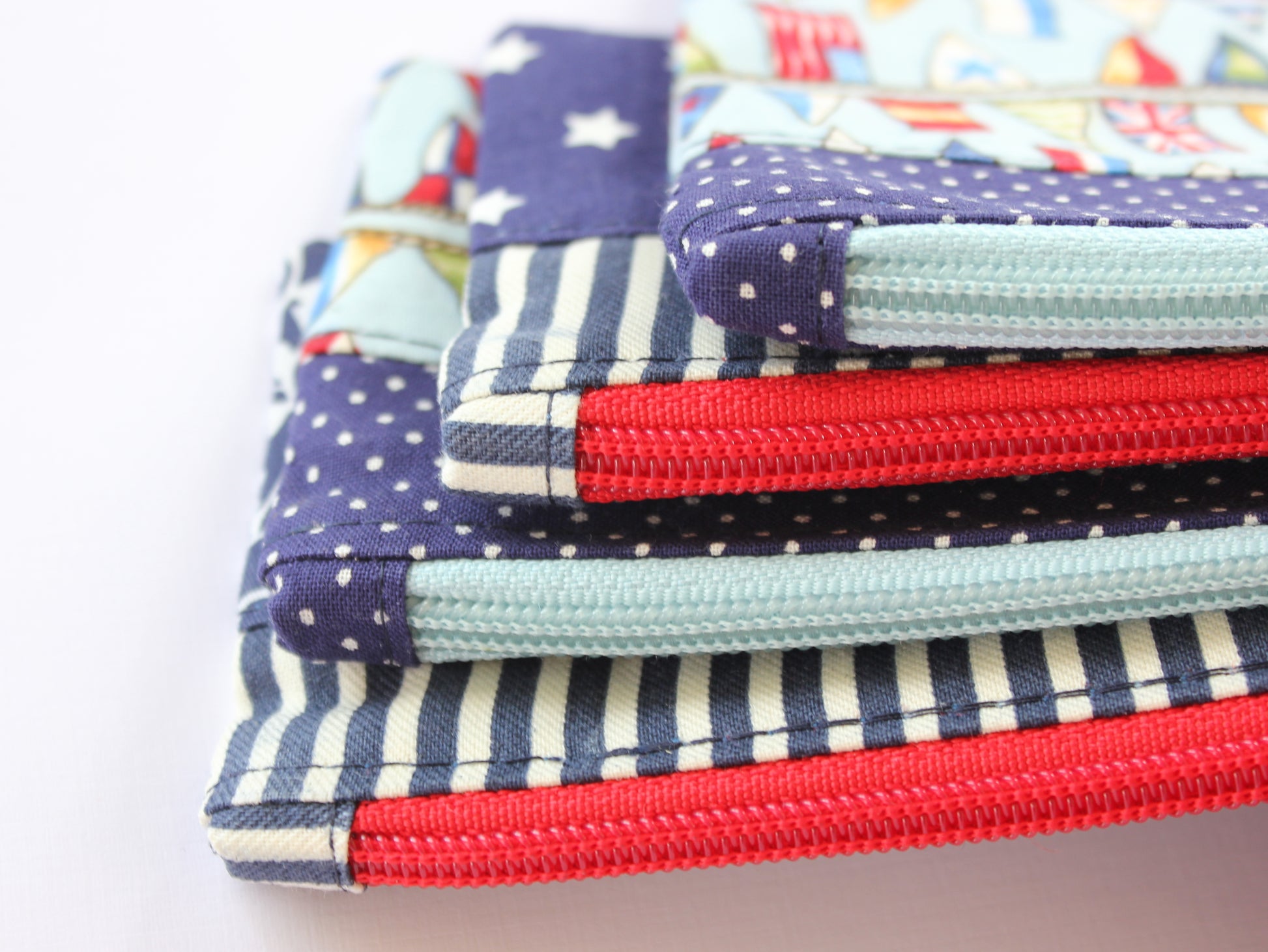 Stack of colorful fabric pouches with zippers by NatkoPatterns