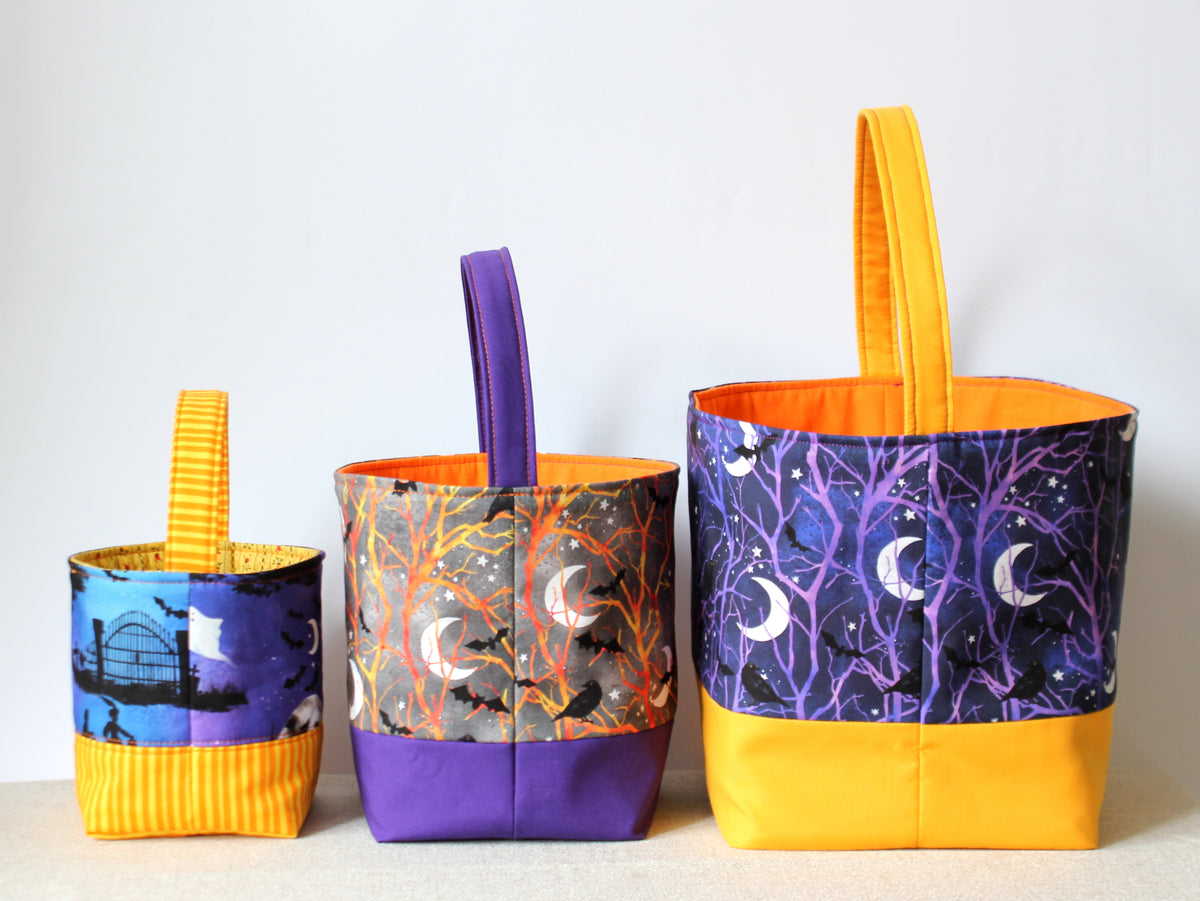 Three handmade Halloween fabric baskets shown folded to demonstrate their shape and compact construction.