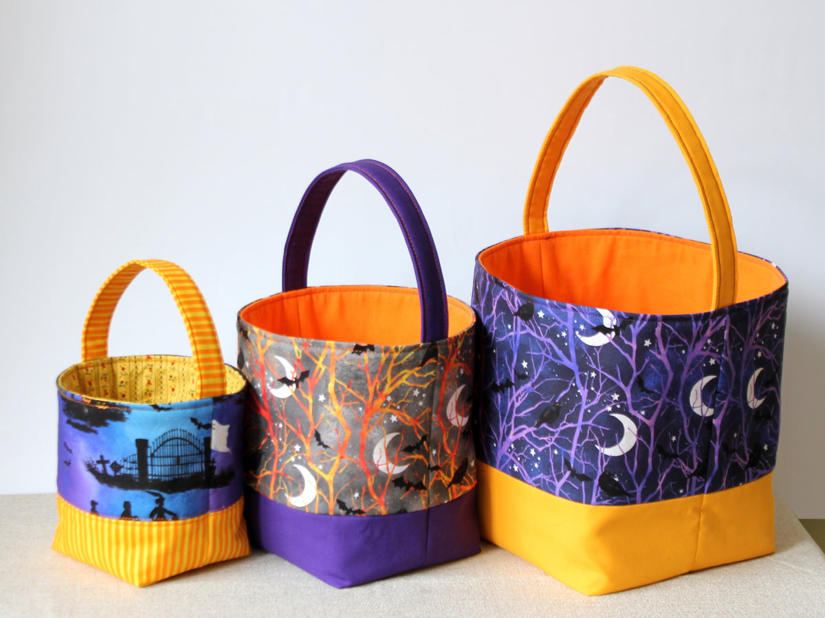 Three reversible Halloween trick or treat baskets showing colorful fabric prints and contrasting yellow and purple details.