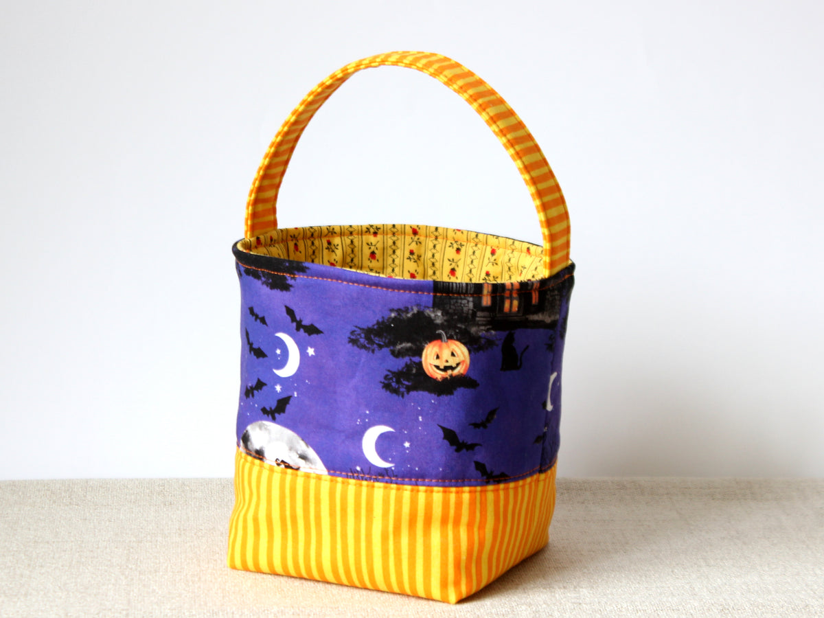 Small Halloween trick or treat basket with a yellow handle, purple Halloween print and contrasting yellow base.