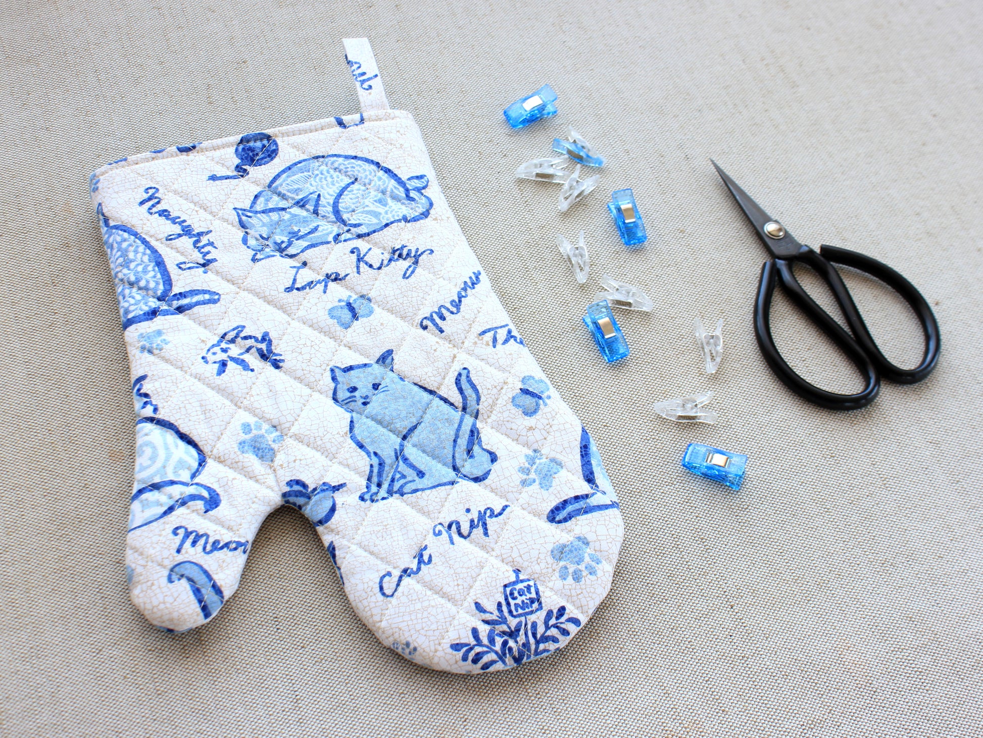 Quilted oven mitt sewing project with fabric clips and sewing scissors