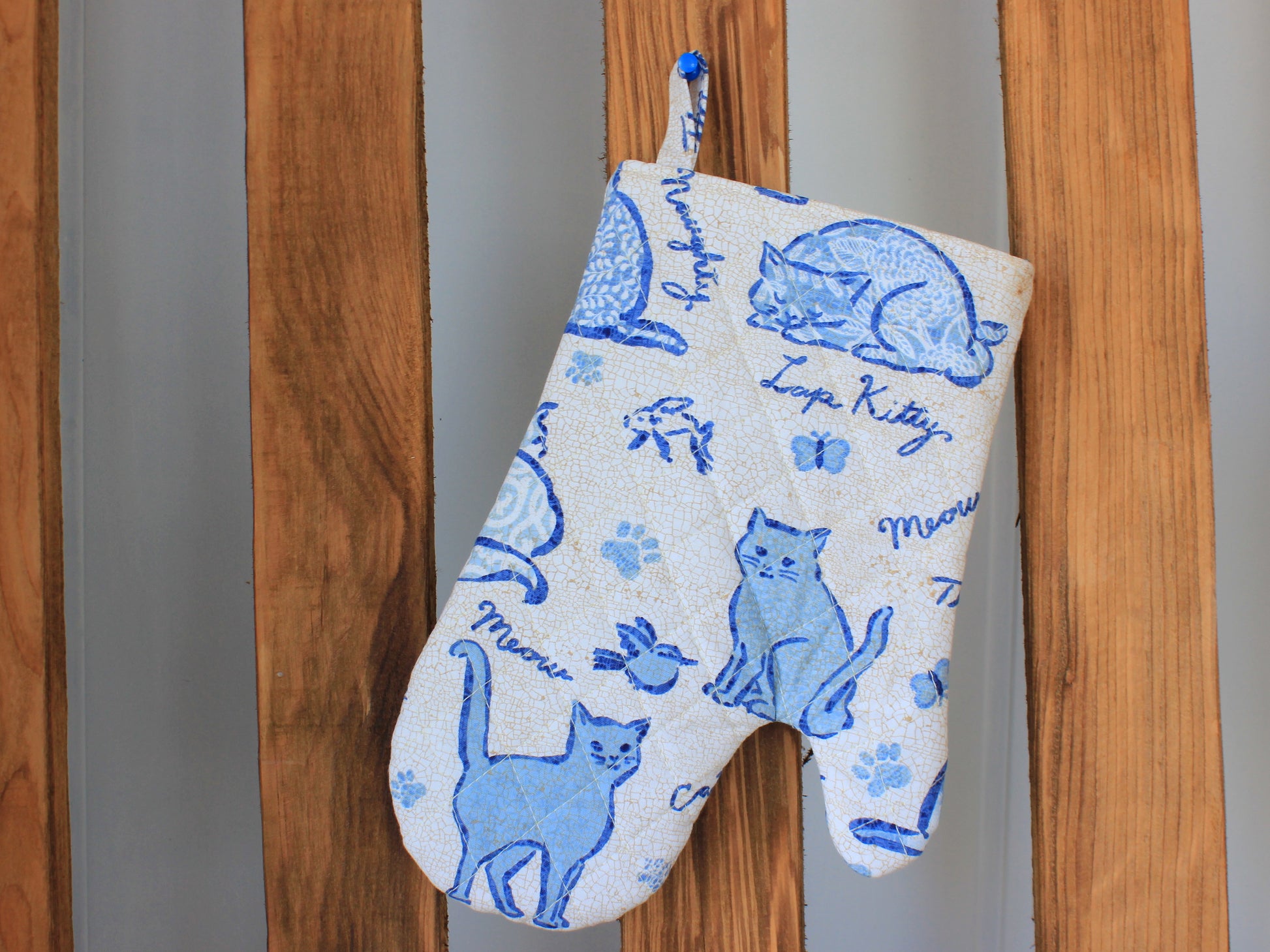 Quilted oven mitt hanging on wooden shelf