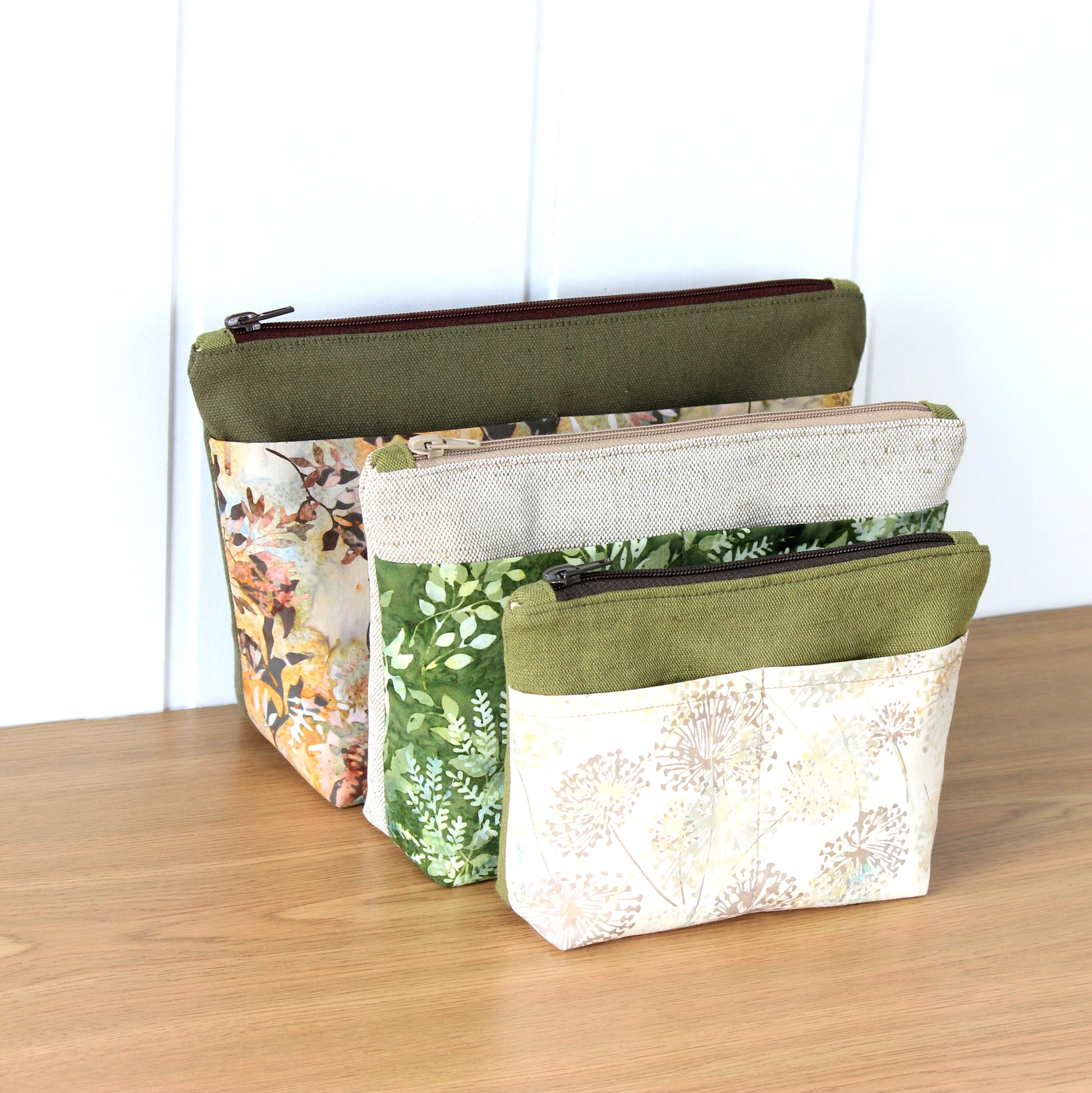Three fabric pouches with different patterns on a wooden surface.